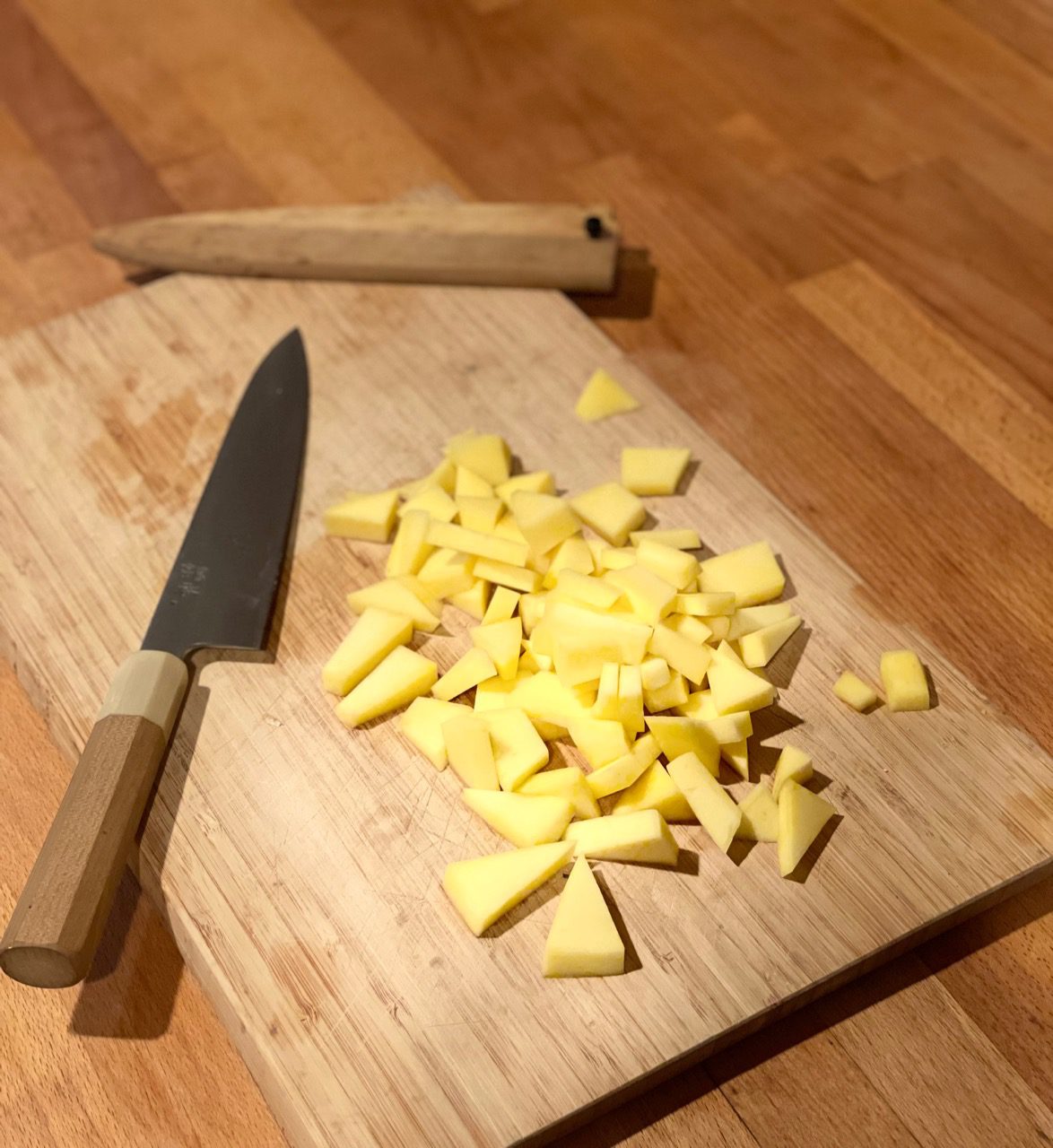 Warm wood cutting board with chopped mango and a beautiful Japanese knife set gently on the surface