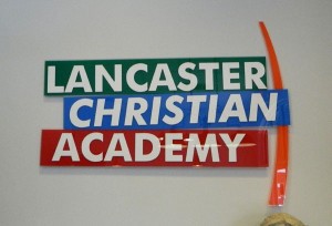 The acrylic in the school's brand colors really stands out against the neutral paint color on the entrance wall.