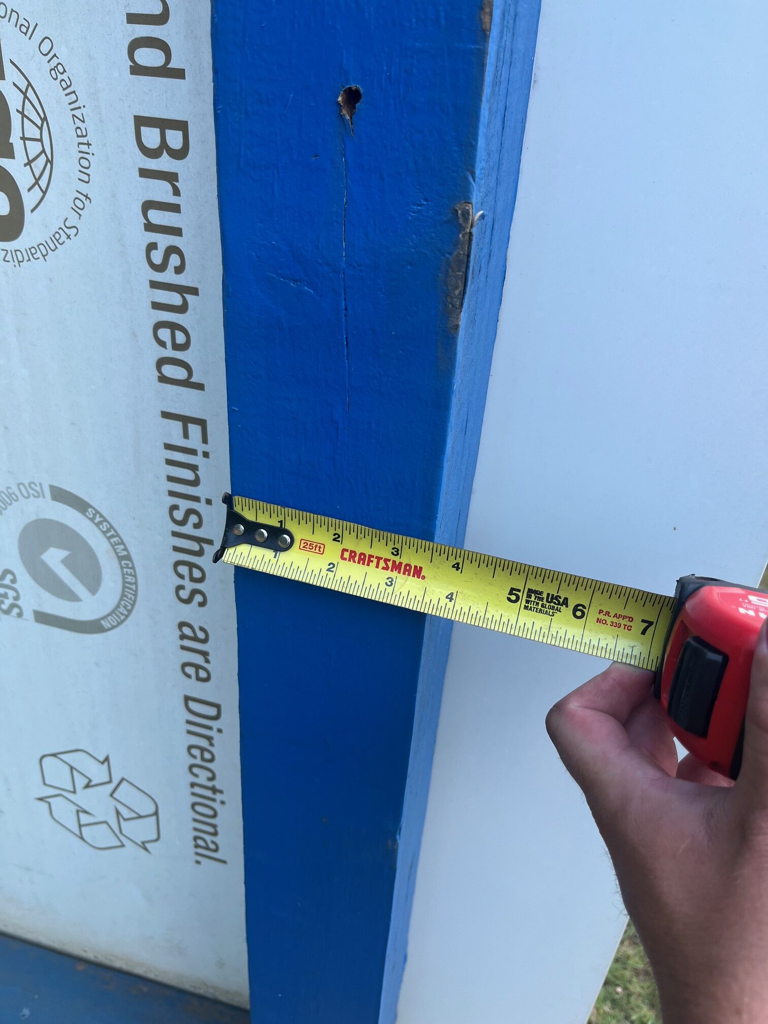 Measuring the thickness of a sign panel with a tape measure during installation