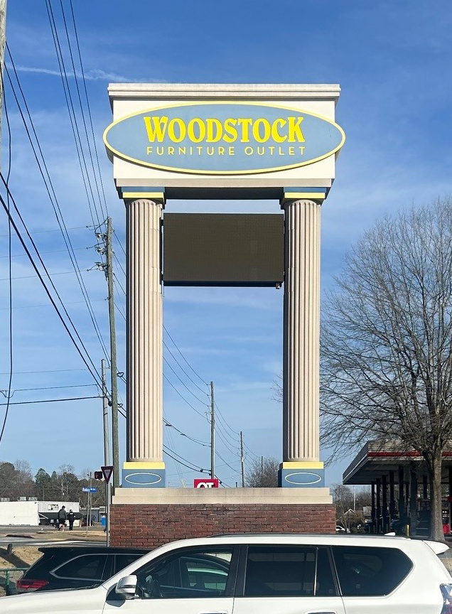Woodstock Furniture Outlet monument sign before restoration Metro Atlanta showing faded columns weathered appearance before Signs and More transformation