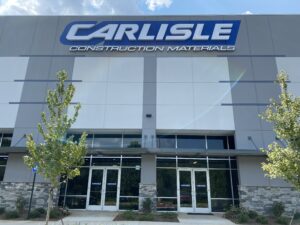 Large blue “CARLISLE” channel letters with tagline on a modern gray-and-white building façade