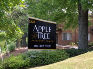 Apple Tree Apartment Homes entrance monument sign in black and gold with address 2328 and phone number 404-349-7988 — apartment complex signage.