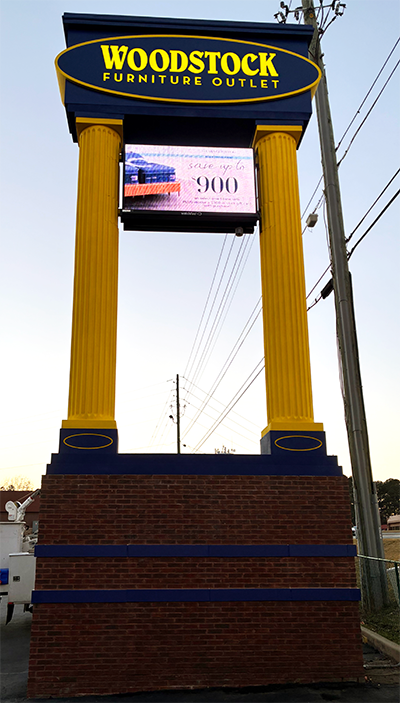 Woodstock Furniture Outlet monument sign after restoration Metro Atlanta with yellow columns navy blue accents by Signs and More